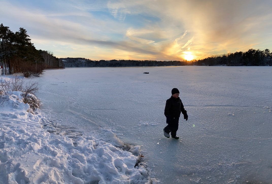 boy walks on frozen scargo lake in winter
