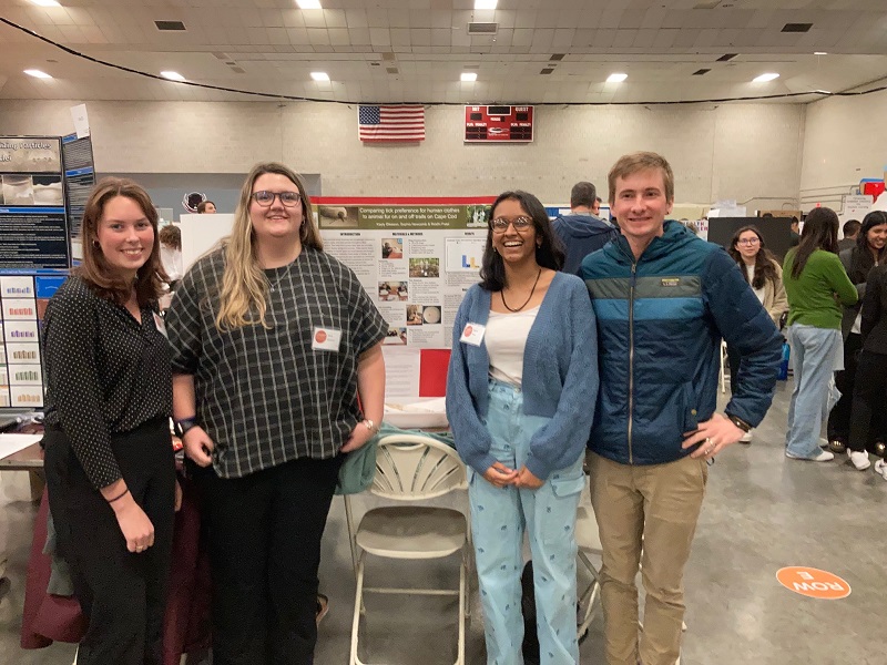 DCLT interns and their mentor pose in front of the project poster at the State Fair.