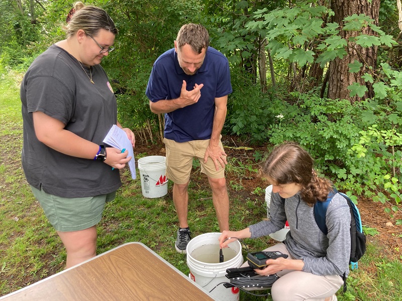 Kayly Gleason (left), Carl DePuy (middle), and Molly Gedutis measure water quality as a part of Molly's experiment.